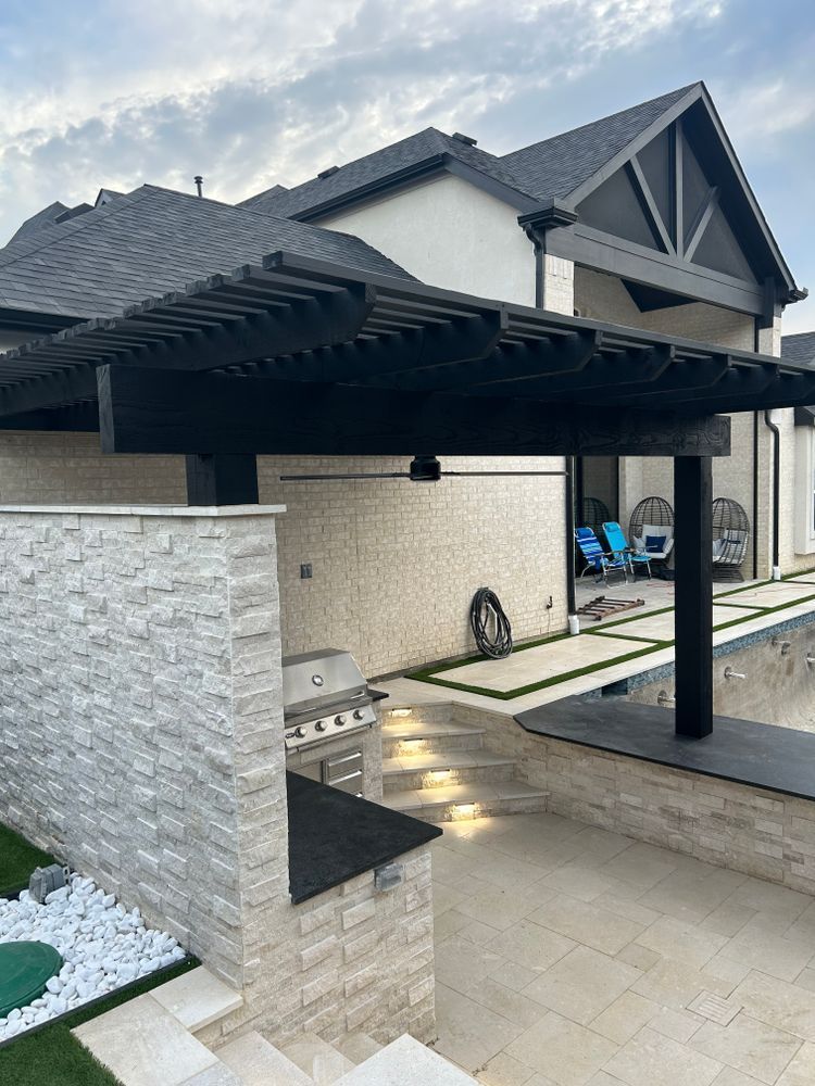 Modern house patio with dark pergola, stone wall, and outdoor seating area