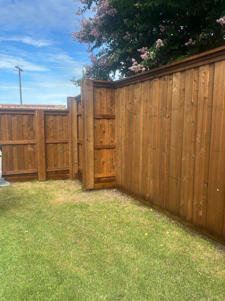 Wooden backyard fence around a grassy yard under a blue sky.