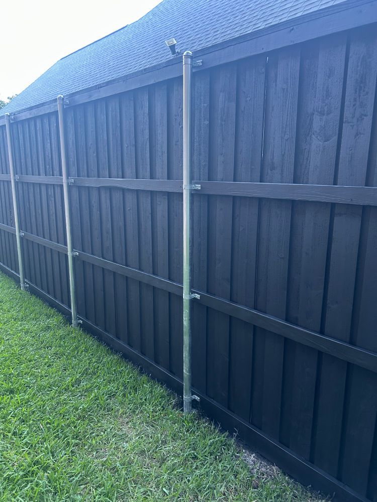 Black wooden fence beside green grass along the side of a house