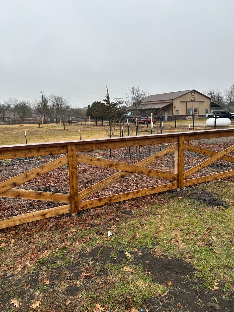 Wooden fence in a wet yard beside a house under a gray sky.