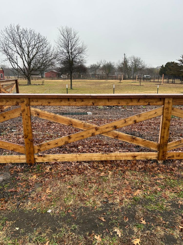 Wooden fence with X-braces in a muddy field under a gray, overcast sky