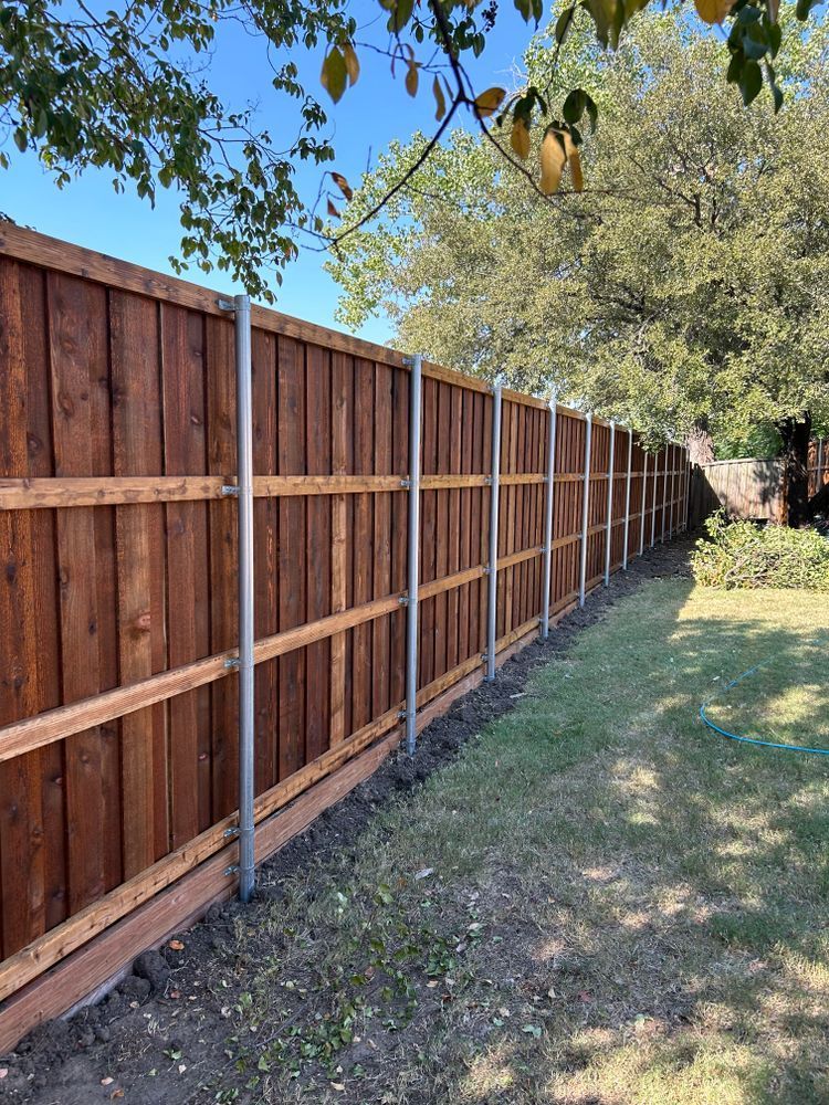 Long wooden privacy fence beside a grassy yard with trees overhead