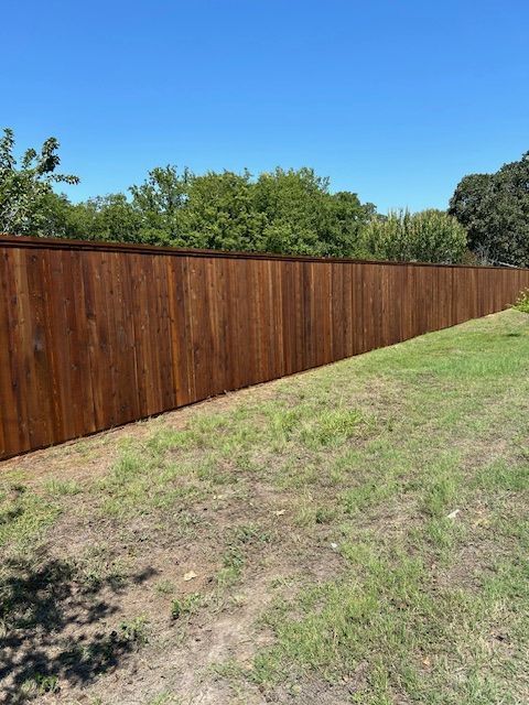 Long wooden fence along a grassy slope under a clear blue sky