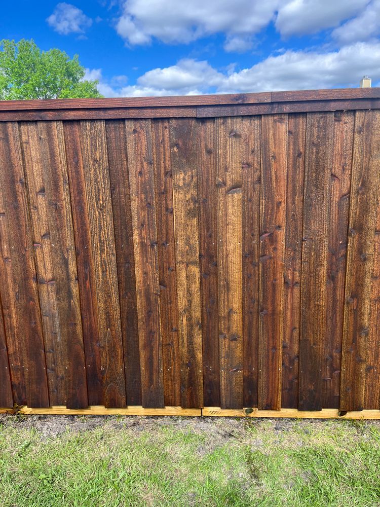 Weathered wooden privacy fence with a blue sky and grass in front