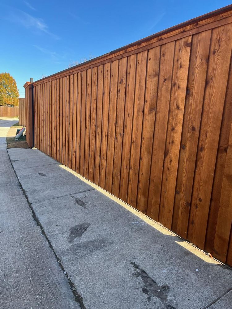 Long wooden fence along a concrete sidewalk on a sunny street corner
