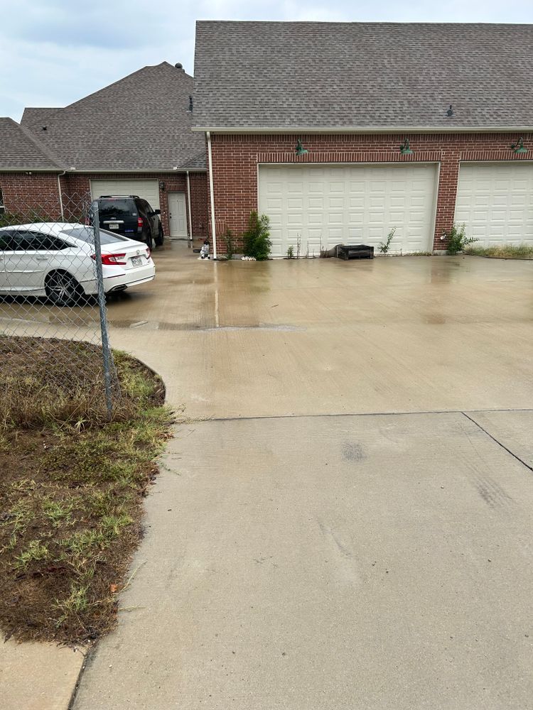 Wet suburban driveway with a parked silver car and brick garage doors after rain