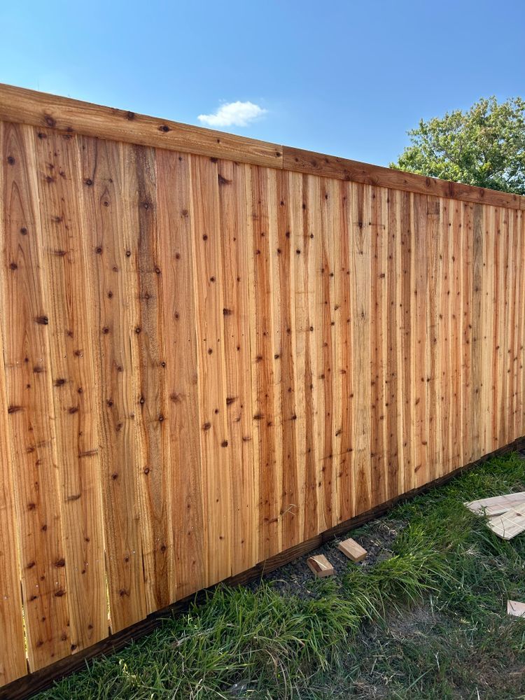 Wooden privacy fence along a grassy yard under a blue sky