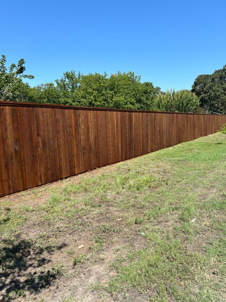 Wooden privacy fence along a grassy slope under a clear blue sky