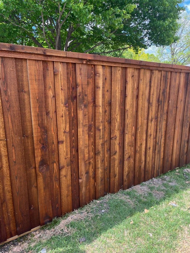 Wooden privacy fence with green grass and trees along the top edge