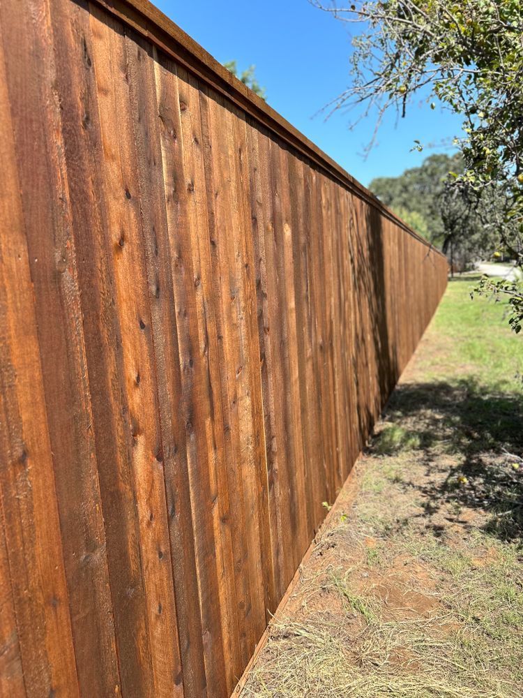Long wooden privacy fence along a grassy yard under a clear blue sky