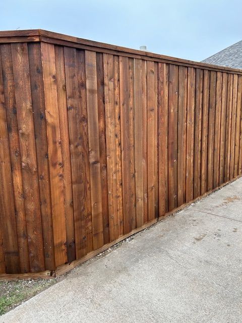 Wooden privacy fence along a concrete driveway beside a house