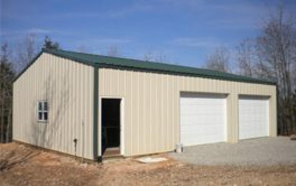A metal garage with two garage doors and a green roof built by A Better Carport's team