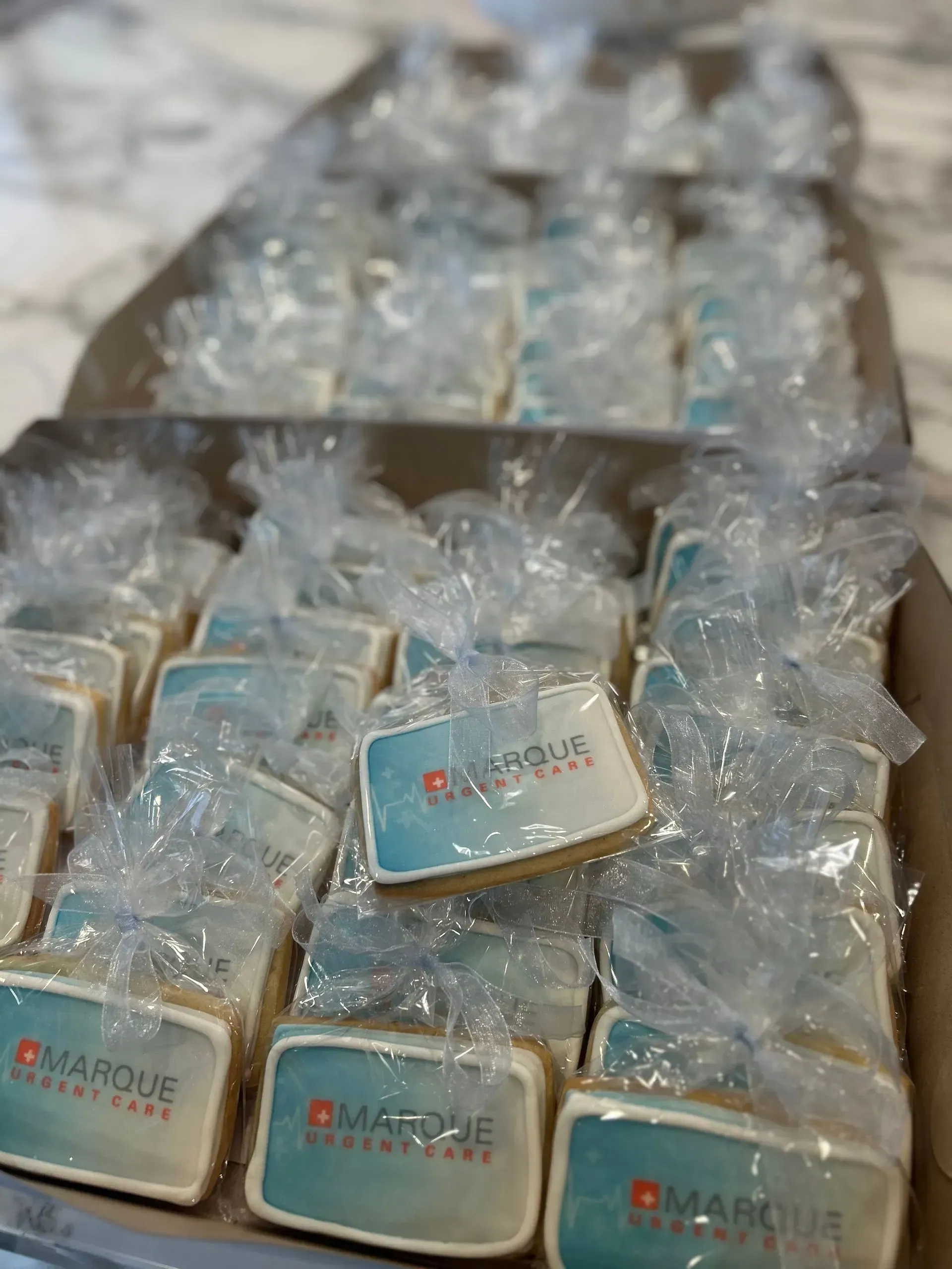 Stacks of clear gift boxes wrapped in plastic, each with a small blue label and red logo.
