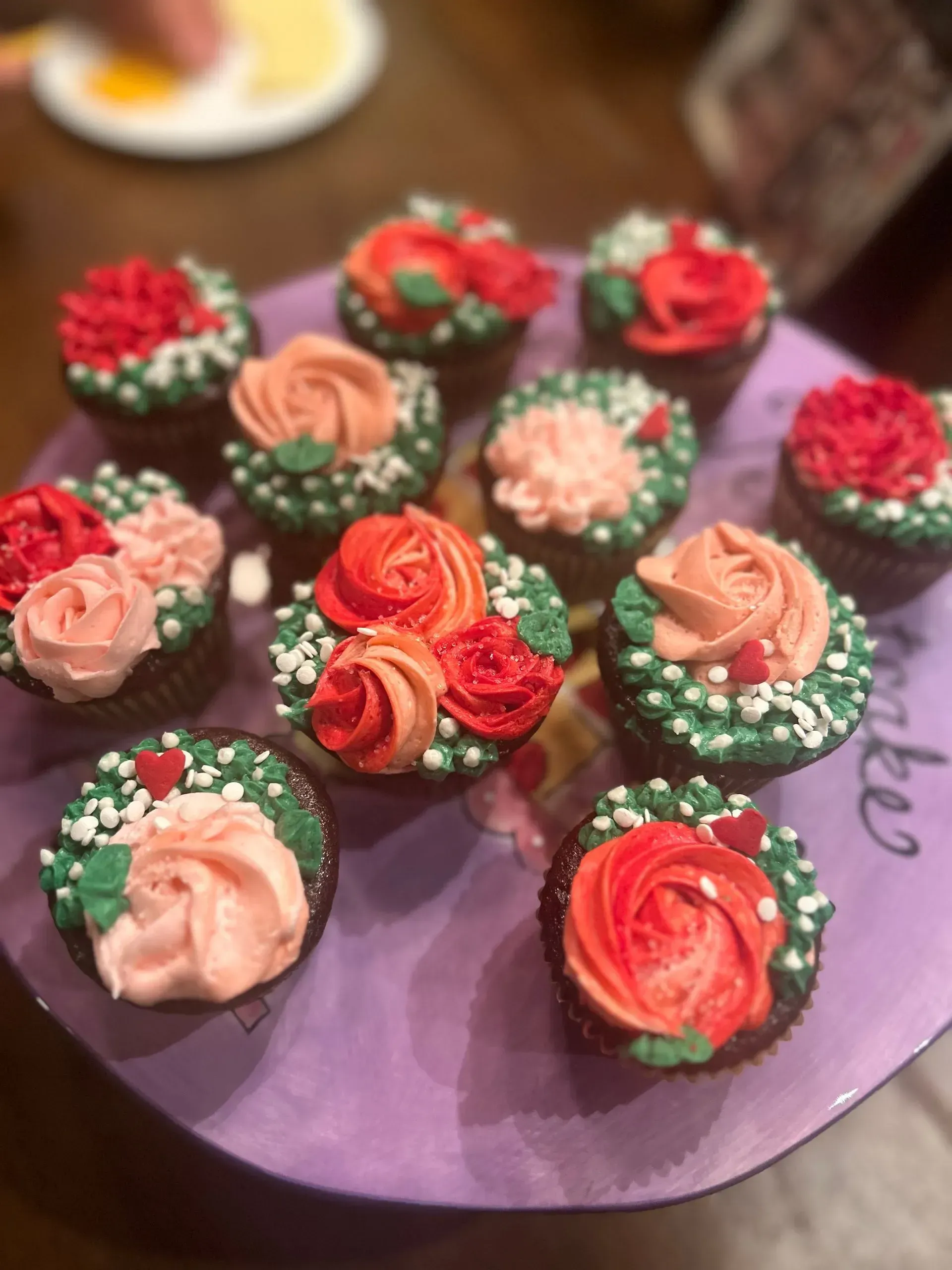 Assorted frosted cupcakes with pink and red swirls on a purple platter
