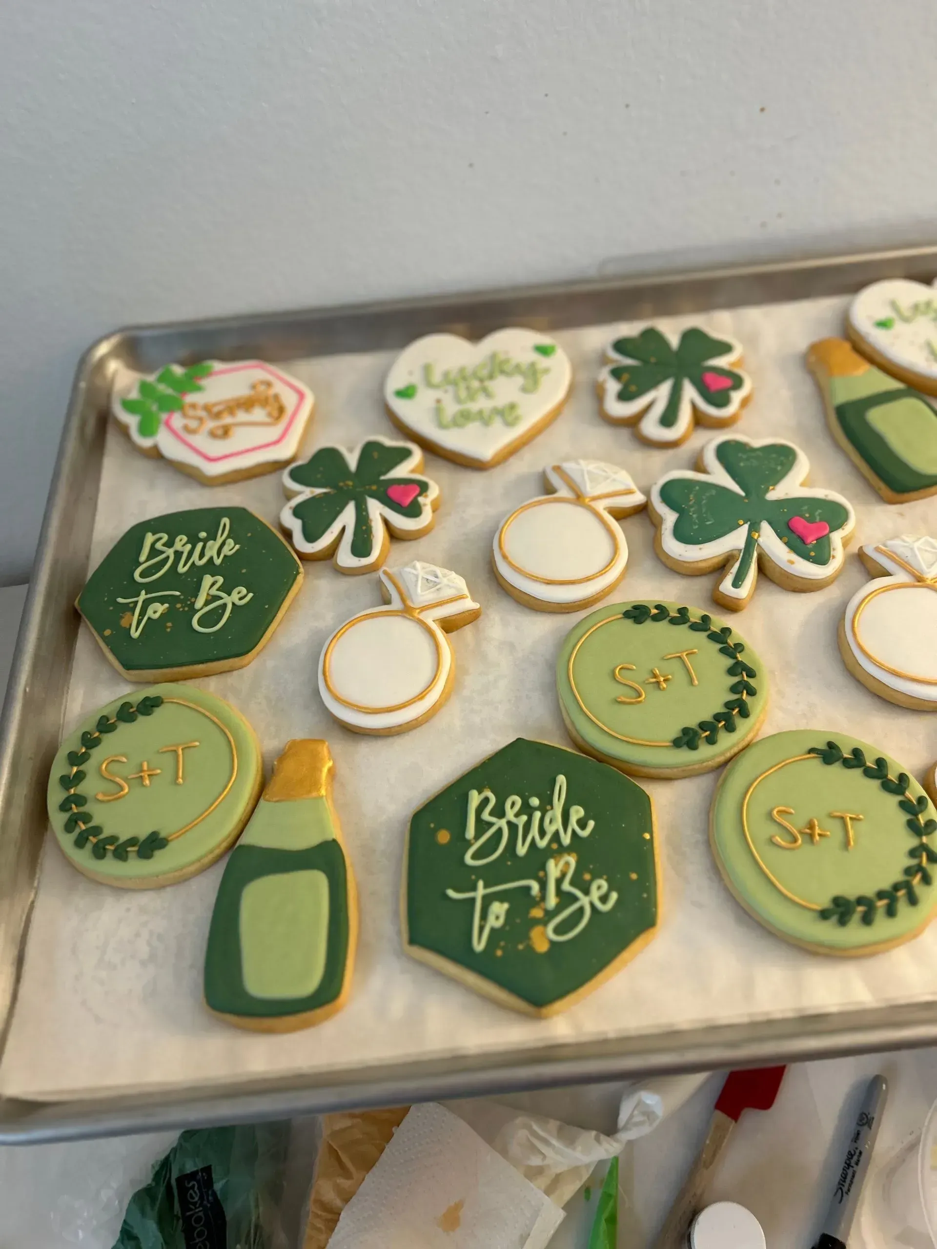 Irish-themed decorated cookies on a tray, including shamrocks, rings, and “Bride to Be” cookies