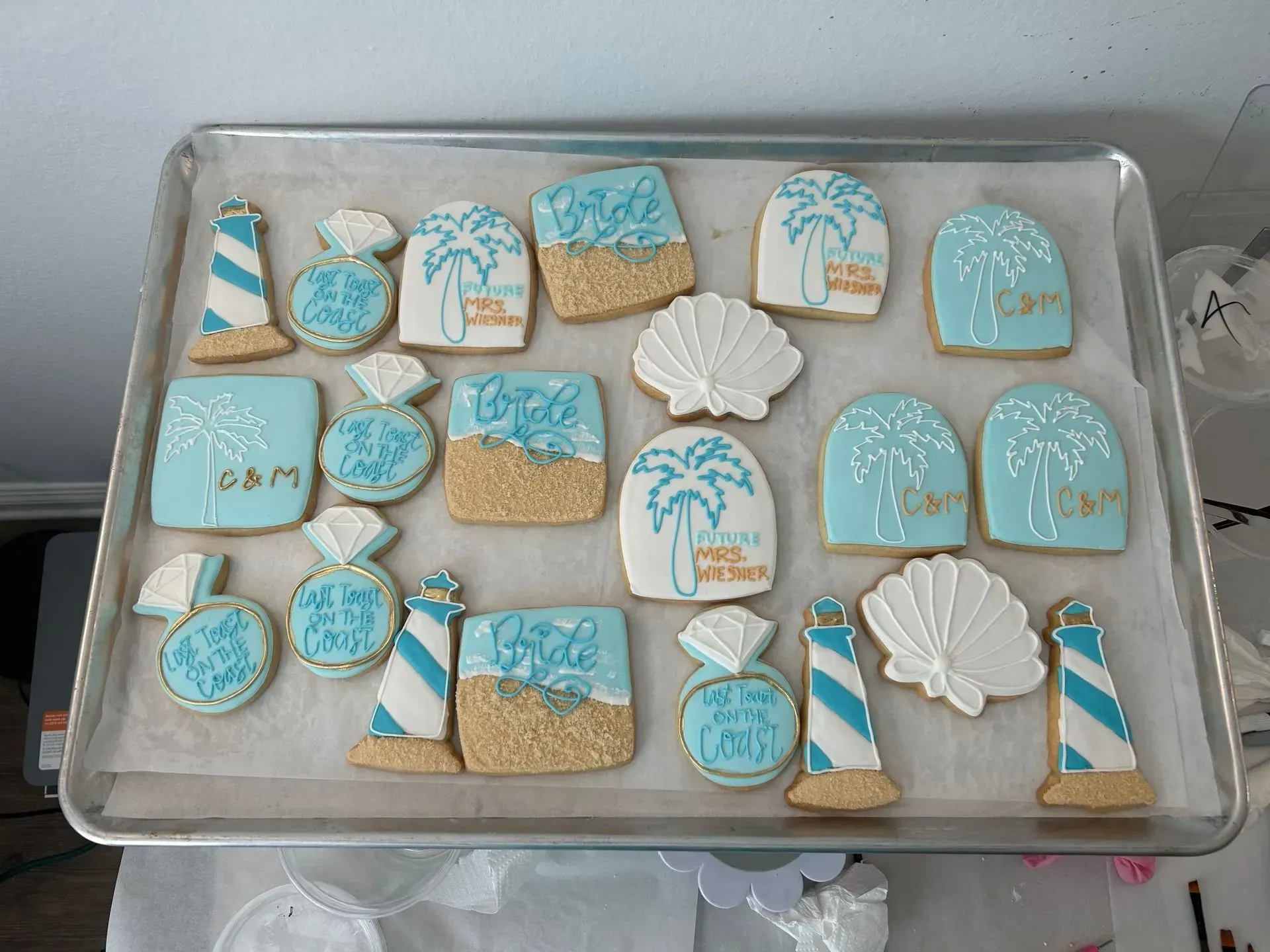 Tray of blue-and-white decorated cookies with palm trees, shells, and beach-themed designs