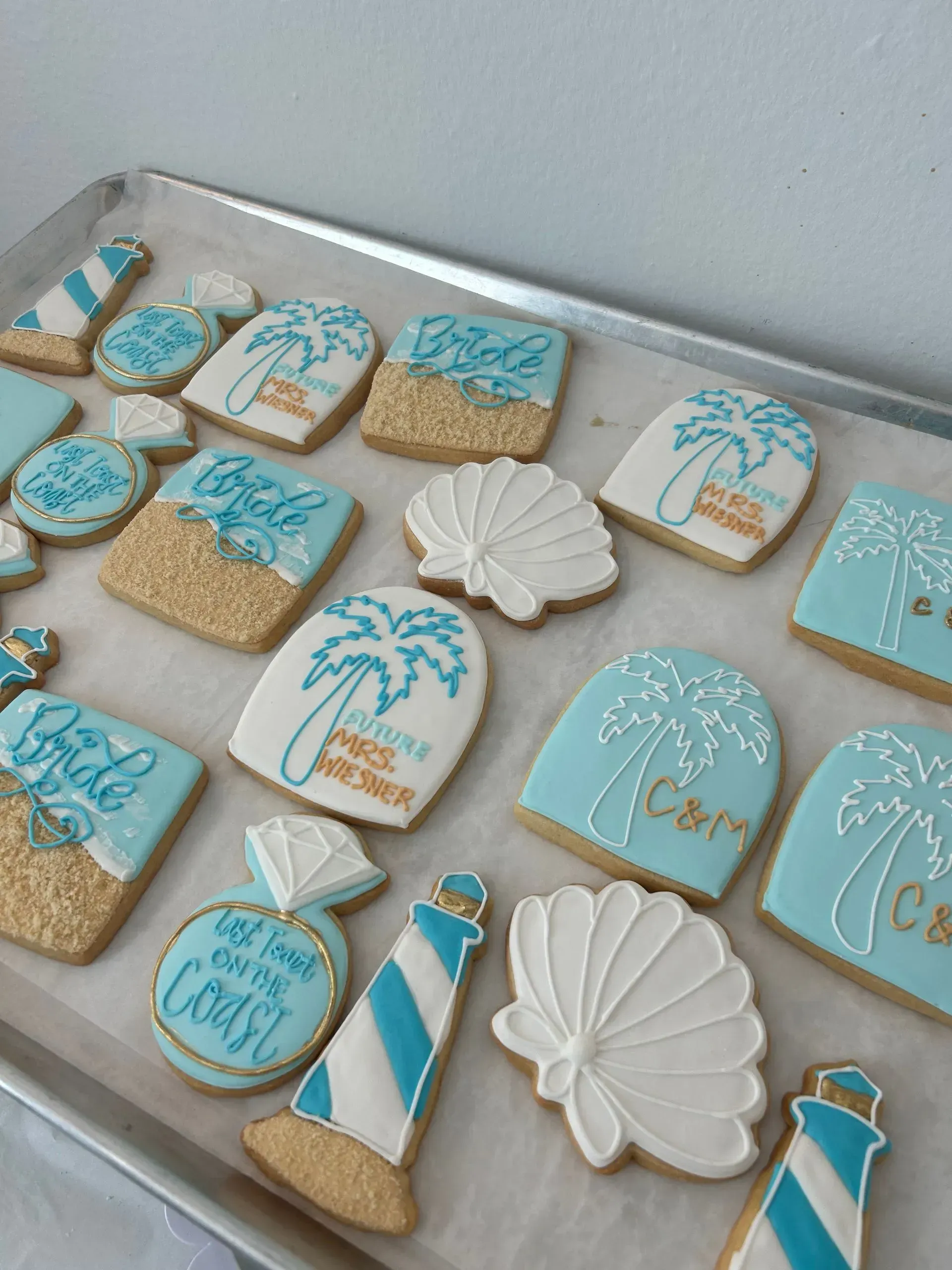 Blue and white seashell, starfish, and palm tree decorated cookies on a tray