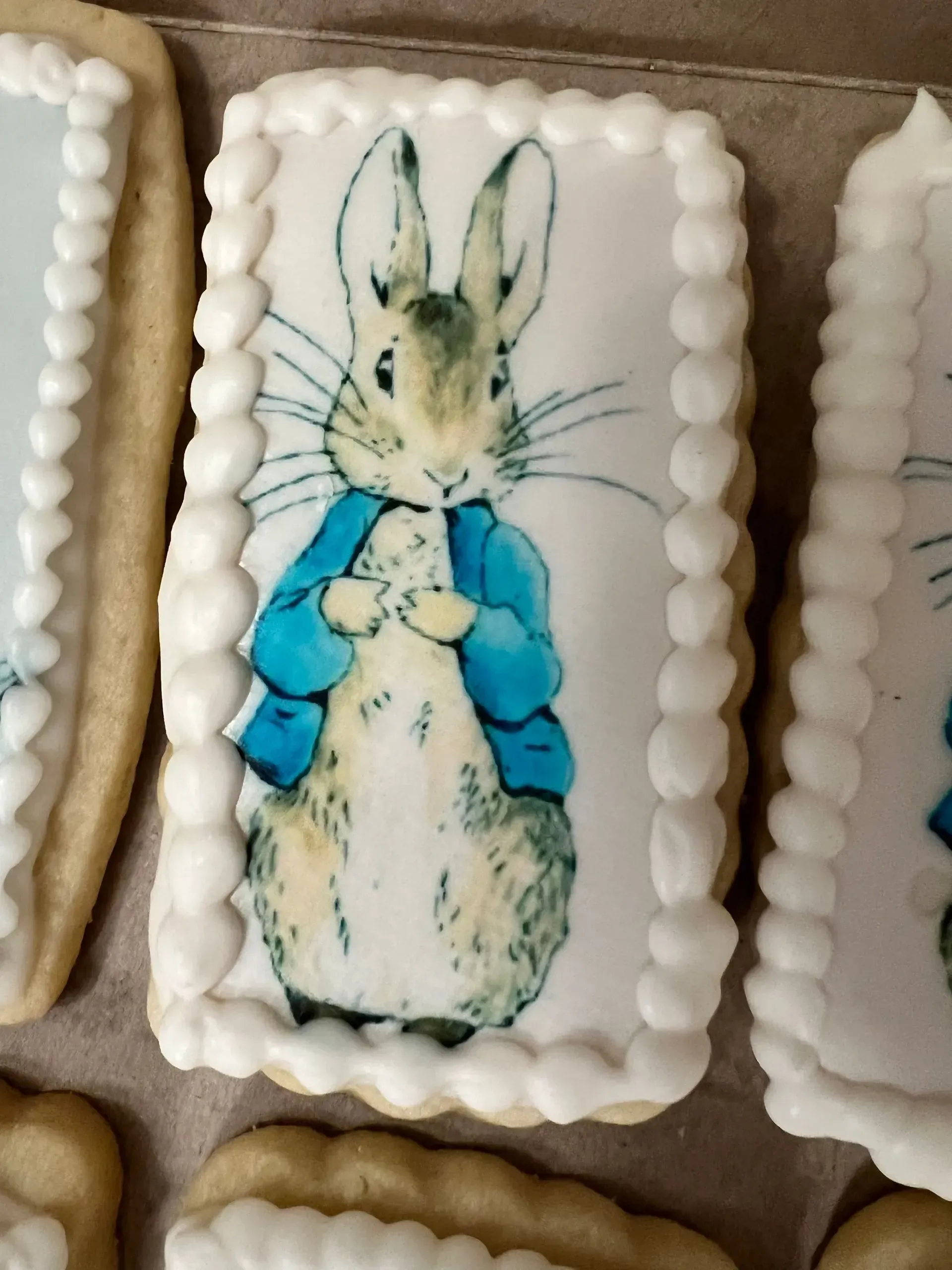Decorated cookie with a watercolor rabbit wearing a blue scarf, surrounded by frosted border