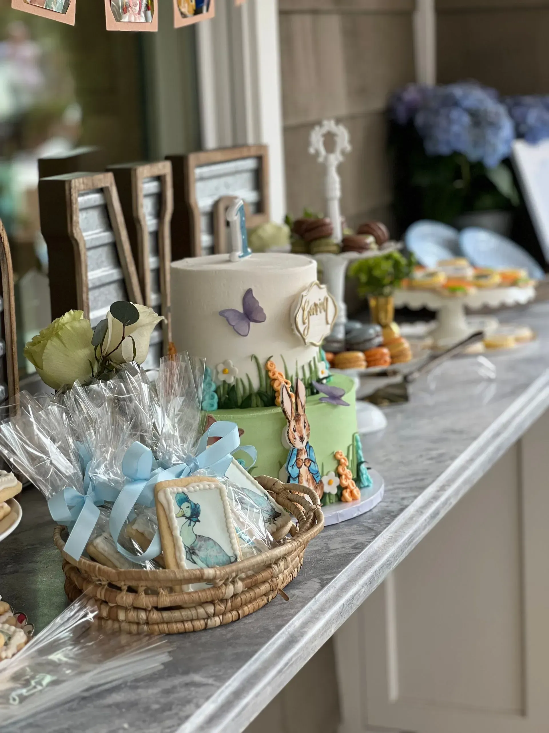Decorated dessert table with a butterfly cake, baskets of treats, and blue floral arrangements