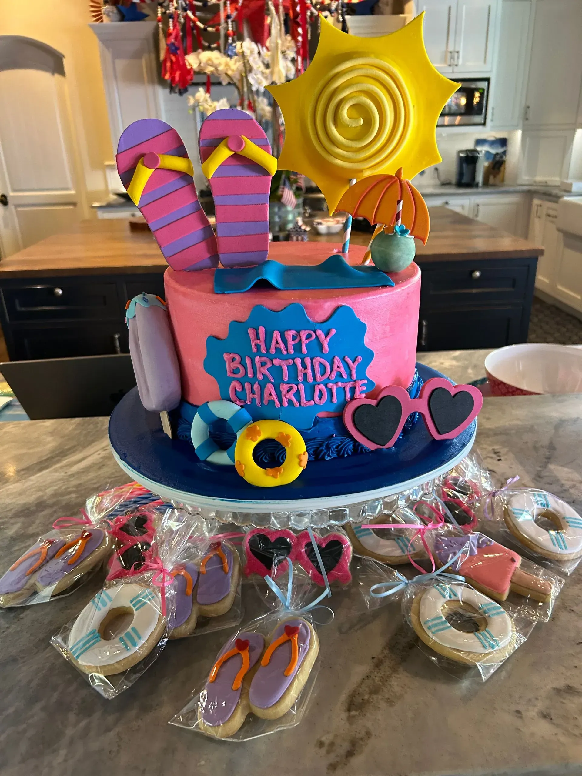 Birthday cake with colorful flip-flop decorations and pink “Happy Birthday” lettering on a kitchen counter