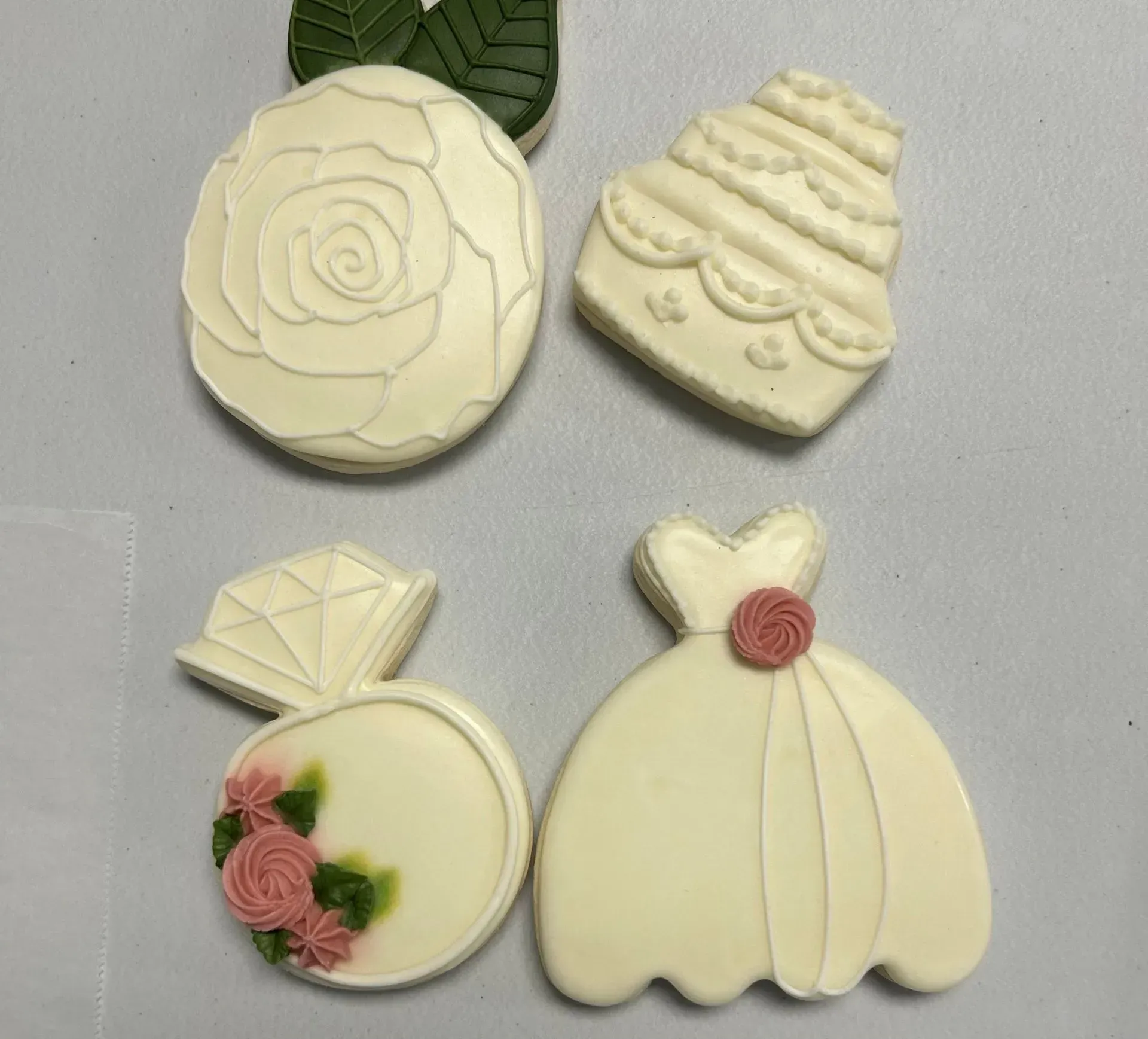 Four cream-colored decorated cookies with floral and dress designs on a gray background