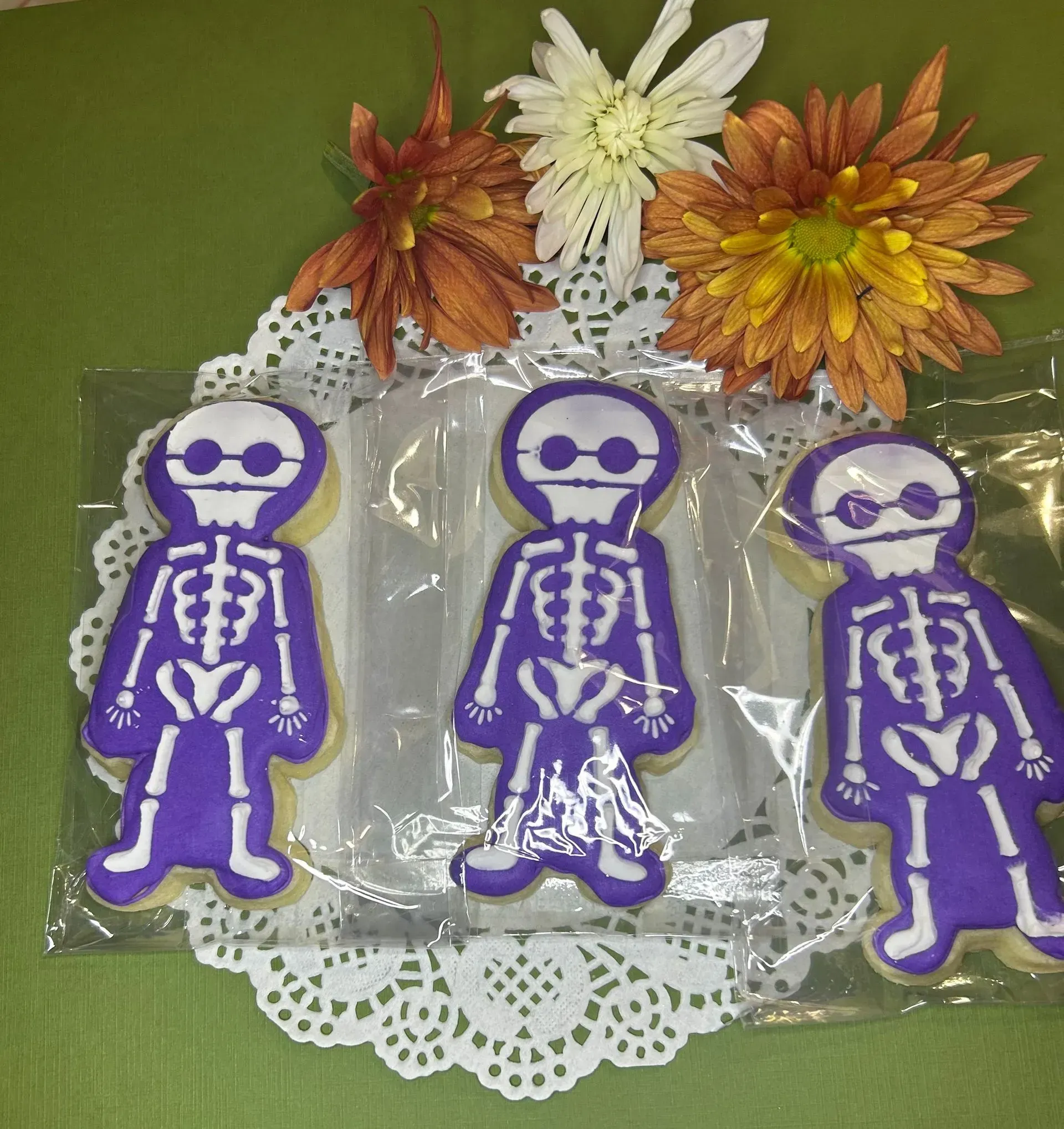 Three purple skeleton stickers on clear packaging with white lace and orange-white flowers above