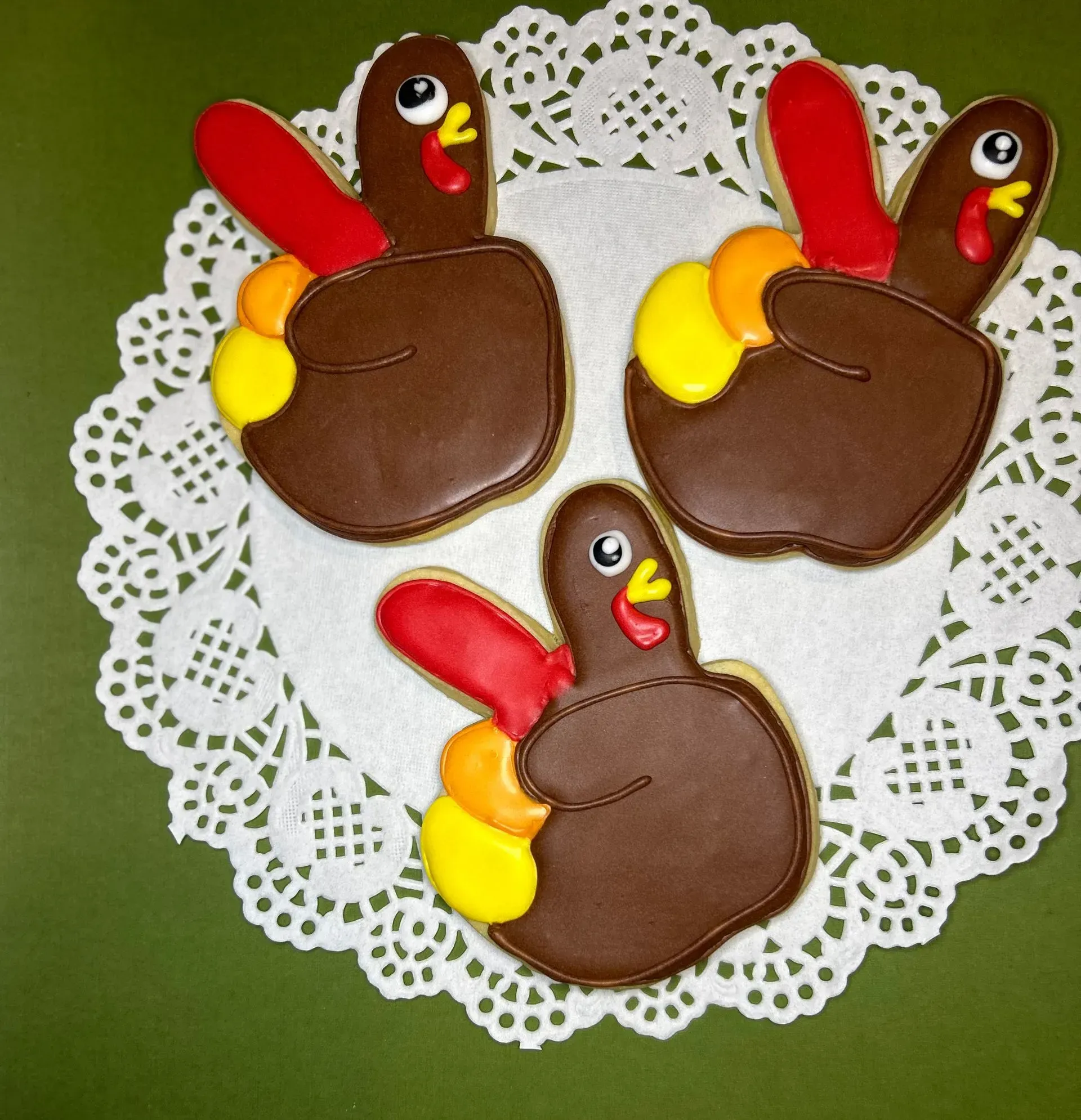 Three turkey-shaped decorated cookies on a white lace doily