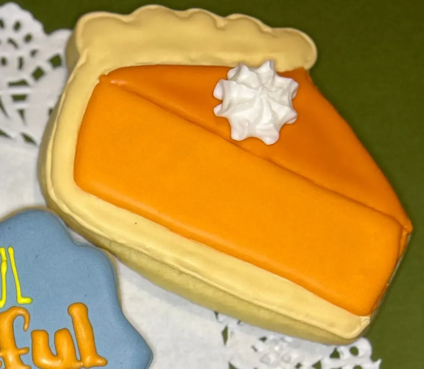 Slice of pumpkin pie-shaped cookie with orange filling and white whipped cream on top