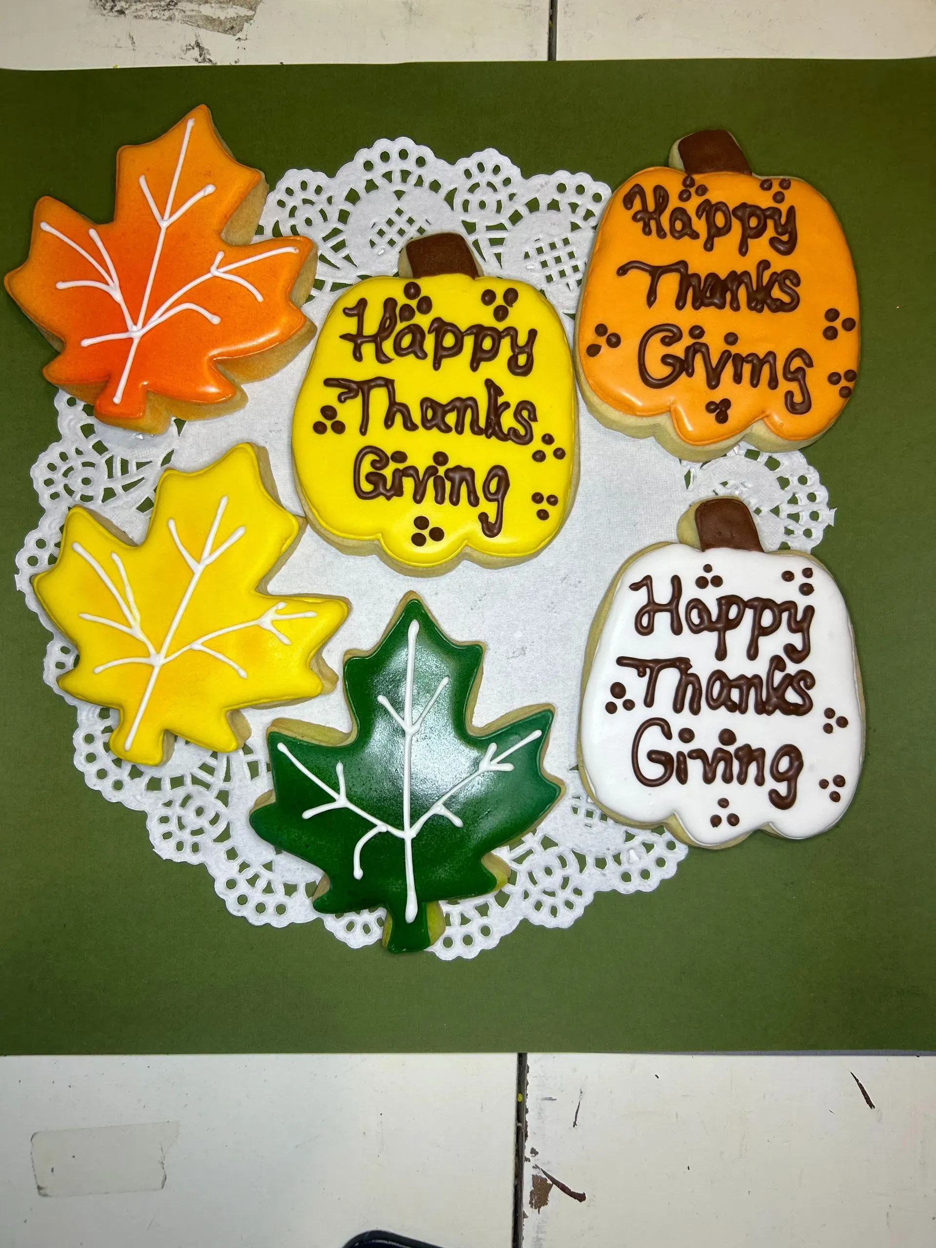 Thanksgiving craft with four leaf cutouts and “Happy Thanksgiving” circles on a lace doily.