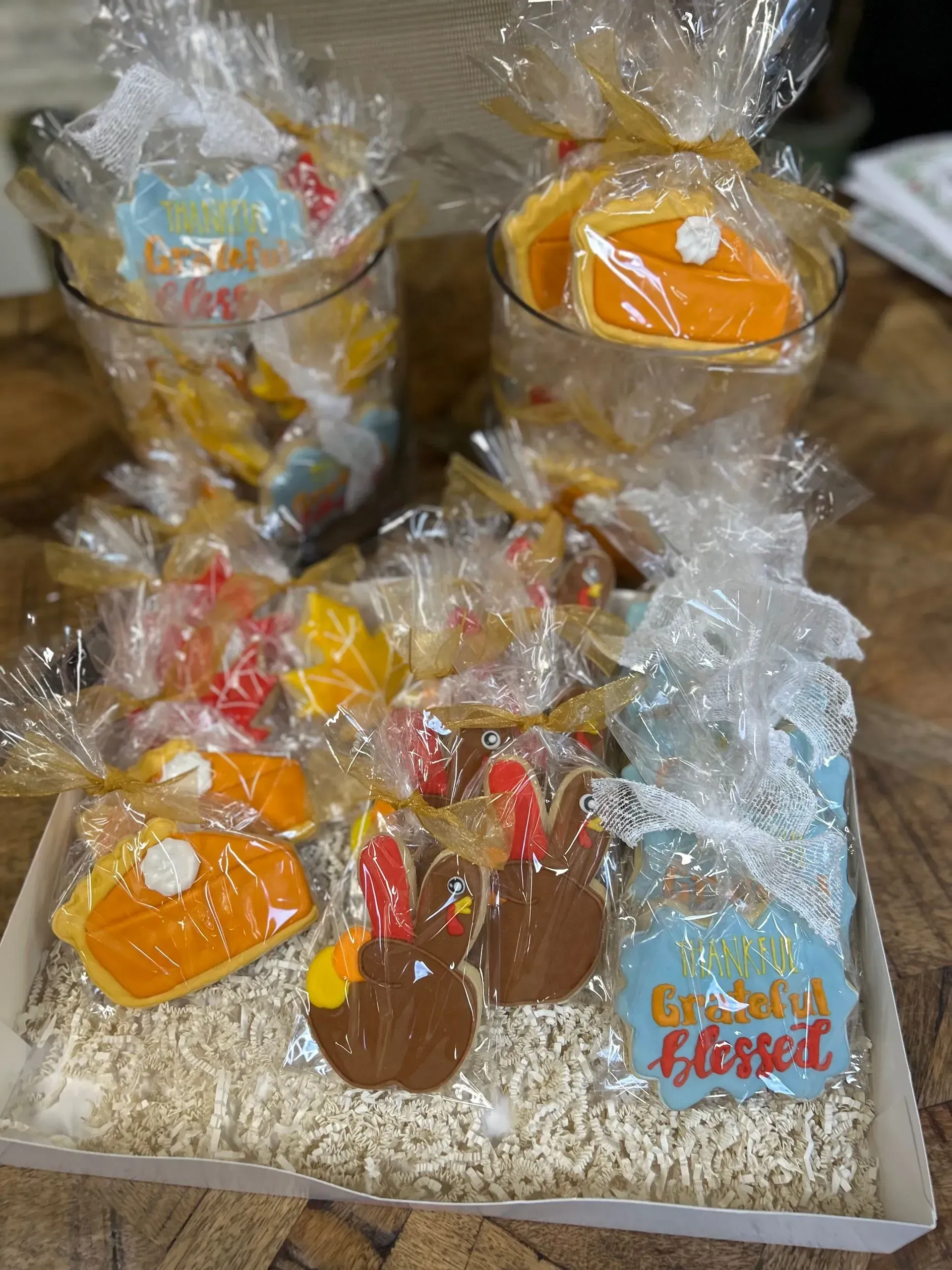 Gift baskets with orange, yellow, and red treats wrapped in clear cellophane on a white surface