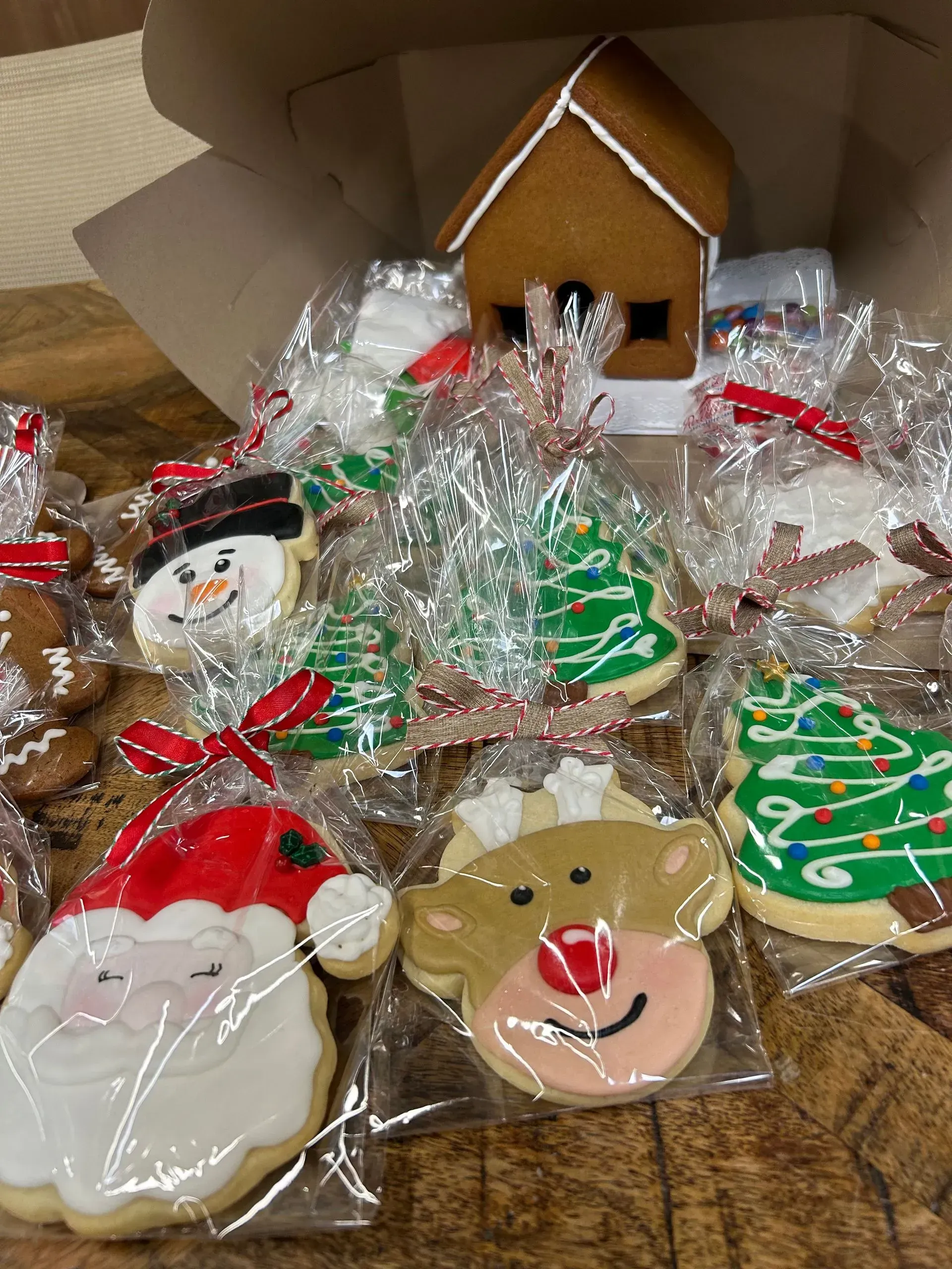 Assorted decorated Christmas cookies with red ribbons and gingerbread house in a box