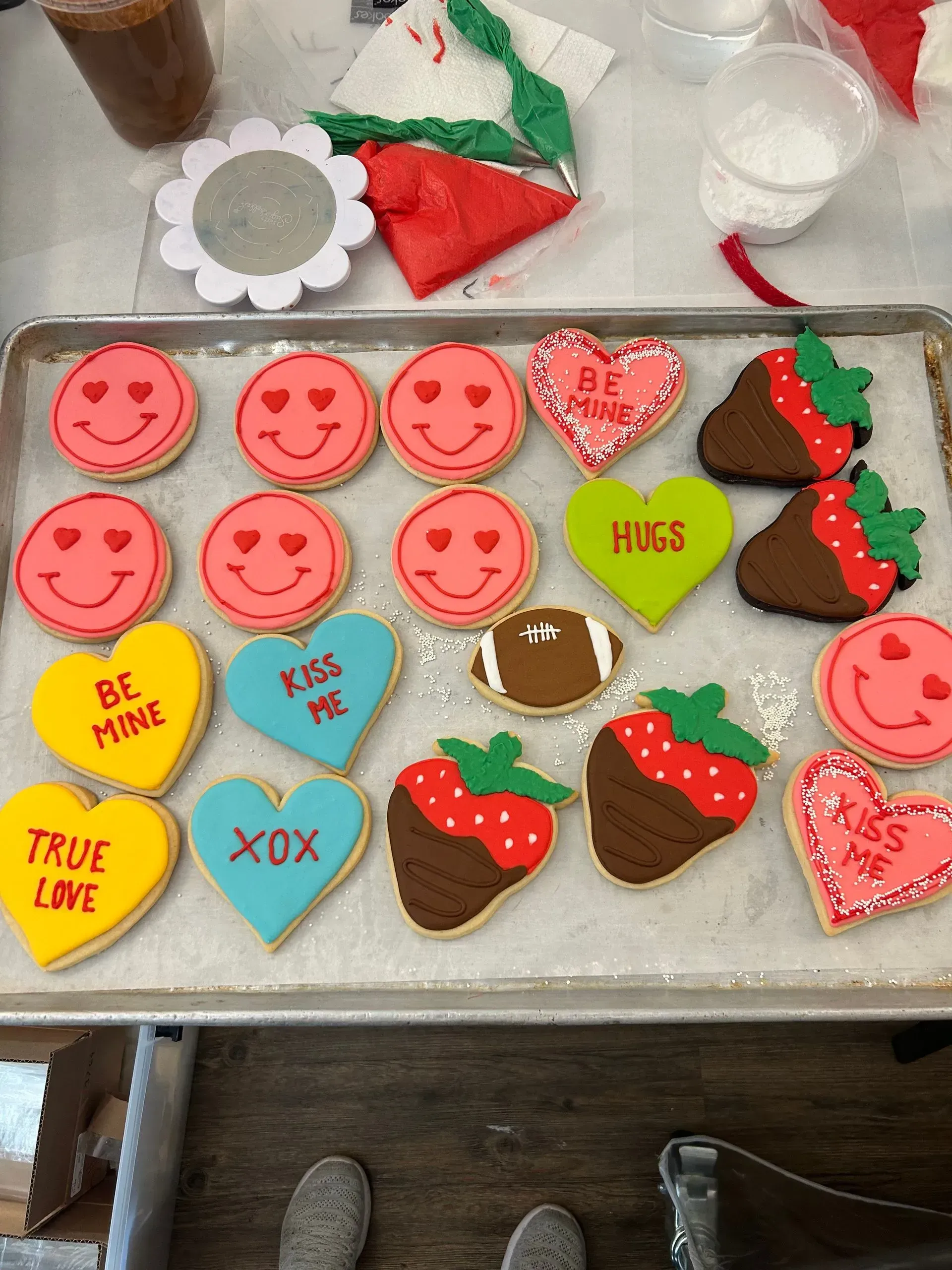 Assorted Valentine’s Day decorated cookies on a tray, including red smiley faces, hearts, strawberries, and messages.
