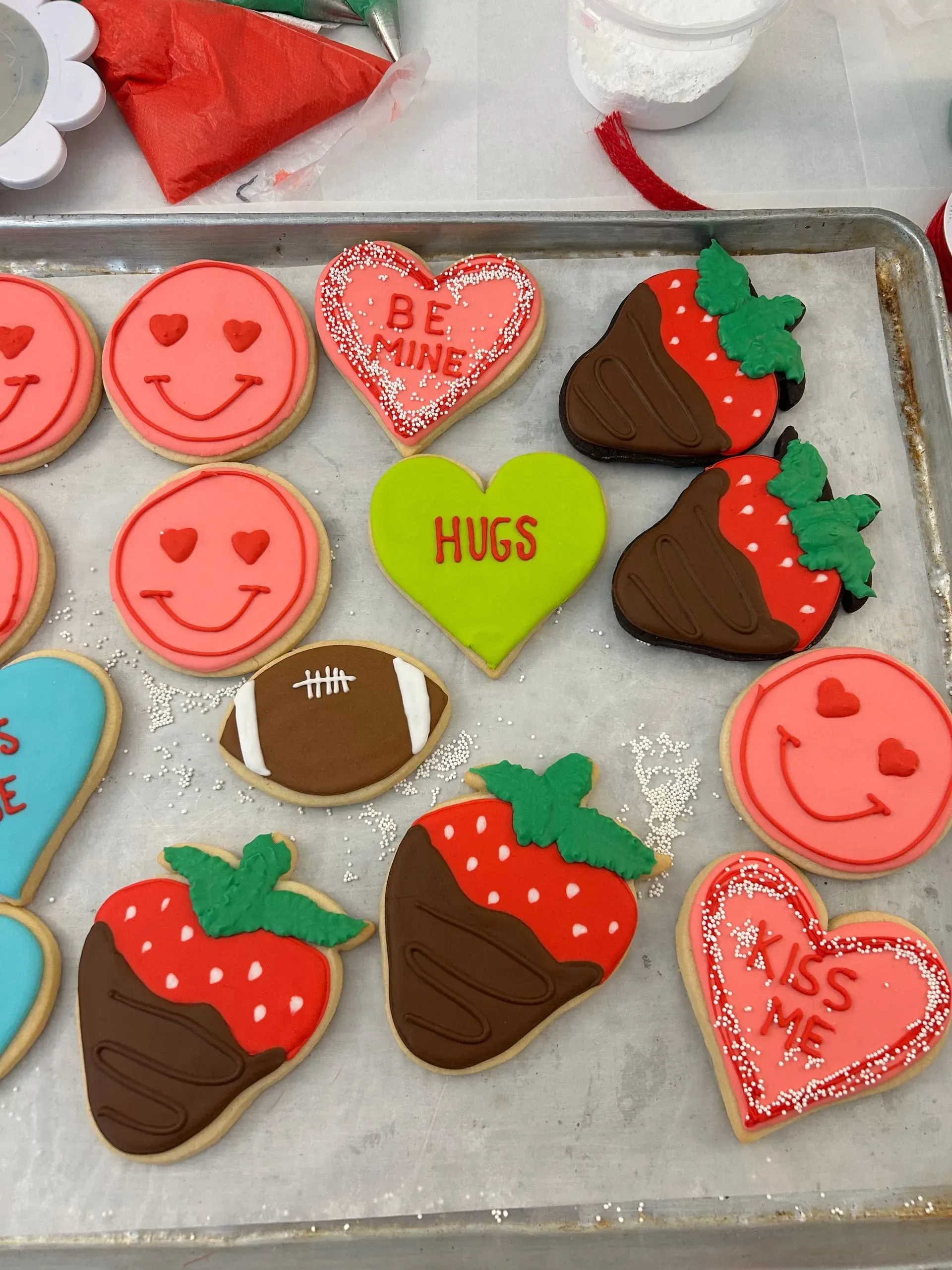 Tray of Valentine’s Day cookies with hearts, smiley faces, footballs, and strawberry-dipped treats