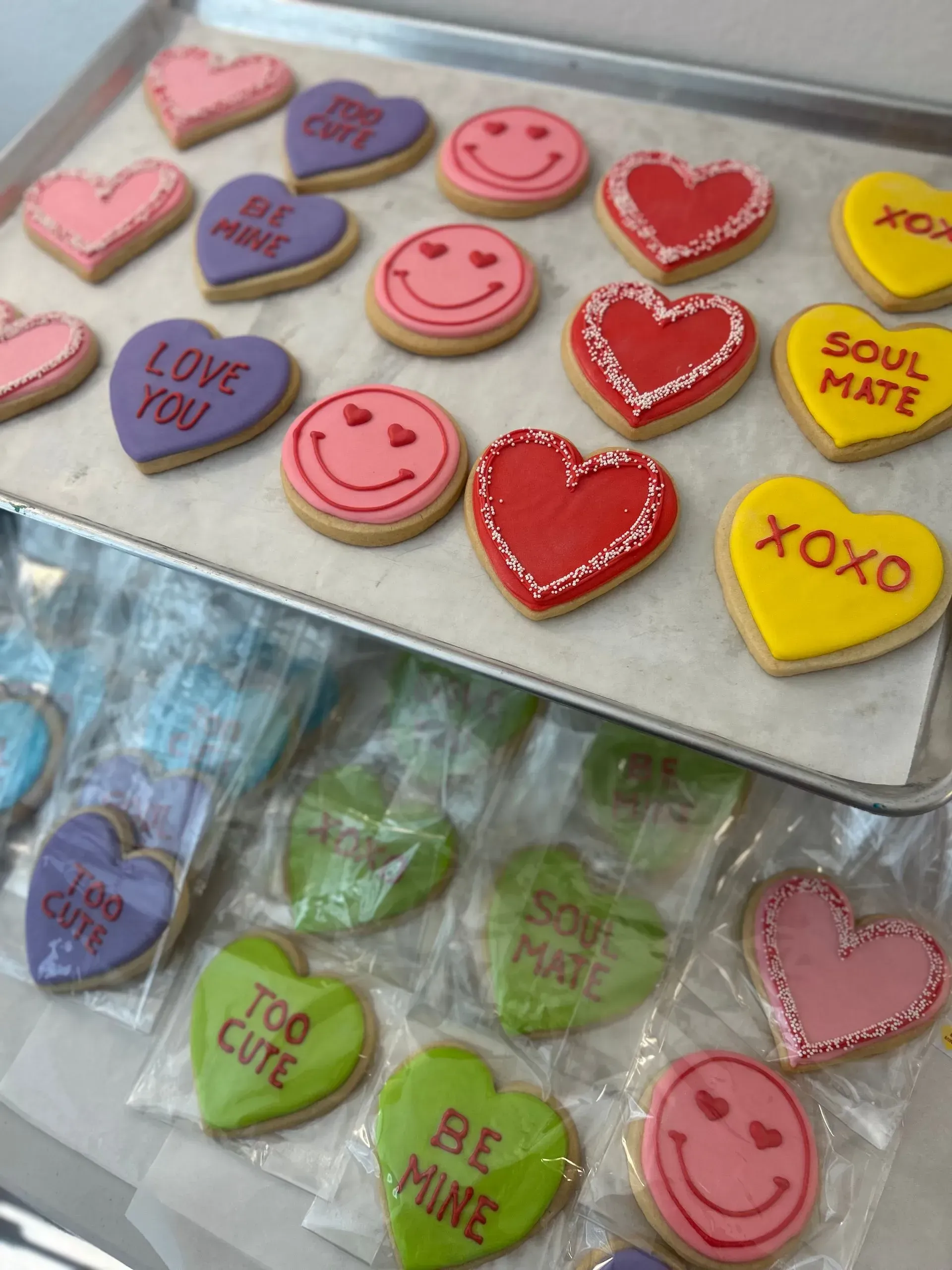 Heart-shaped and smiley candy, colorful conversation hearts arranged in a box and bag