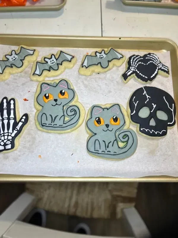 Halloween cookie tray with bats, skulls, spider, skeleton hand, and orange-eyed owl cookies