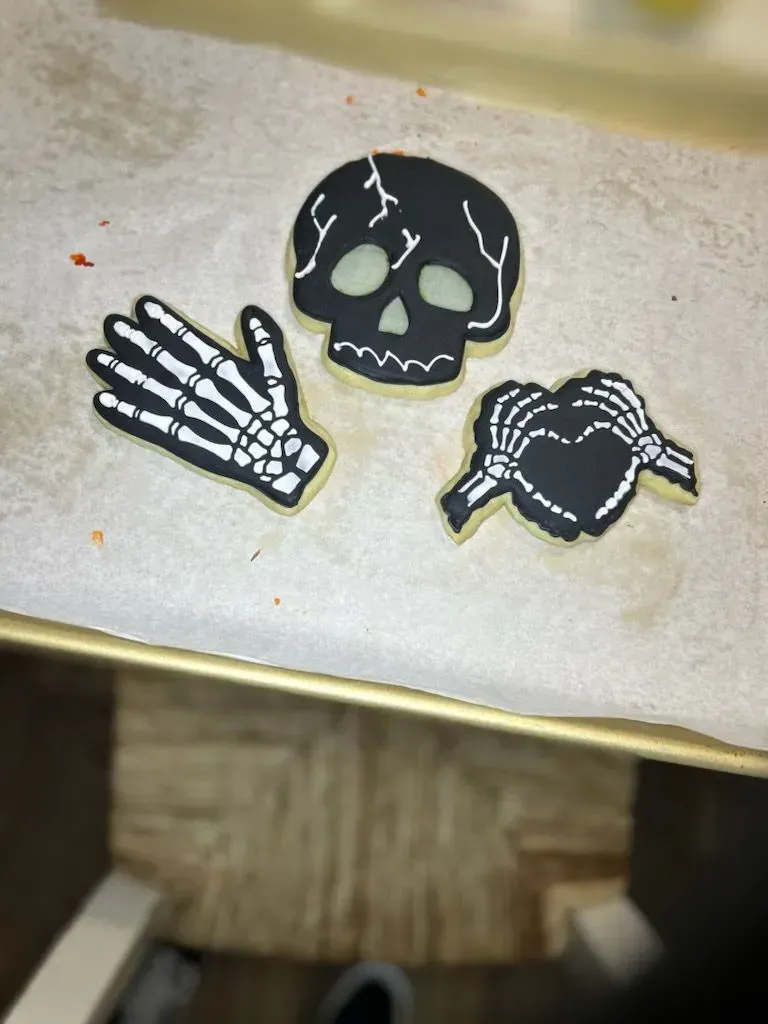 Three skull-and-crossbones patches on a beige surface, including a hand skeleton and a black skull face