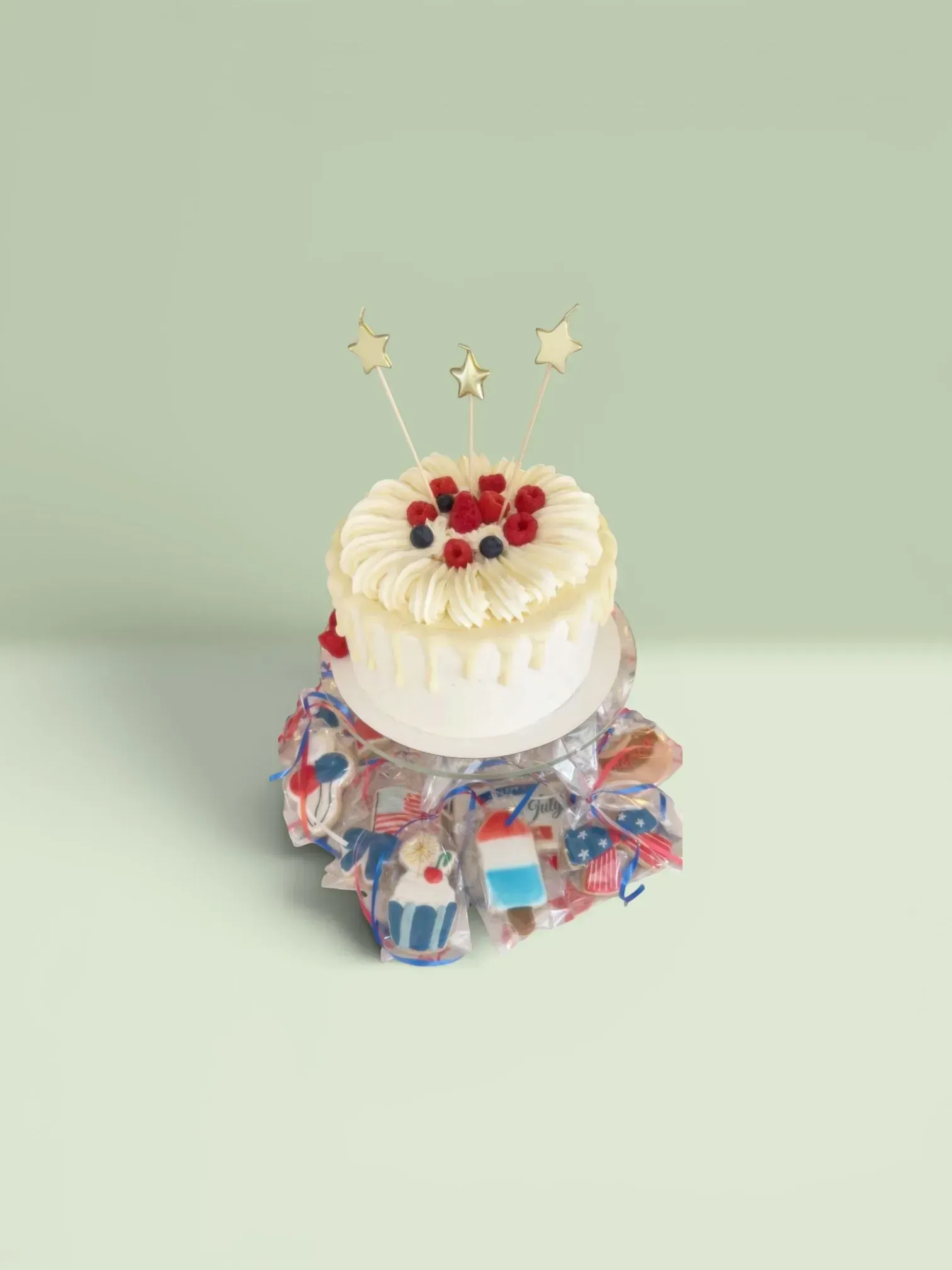 Small white frosted cake with red berries on a decorated stand against a pale green background