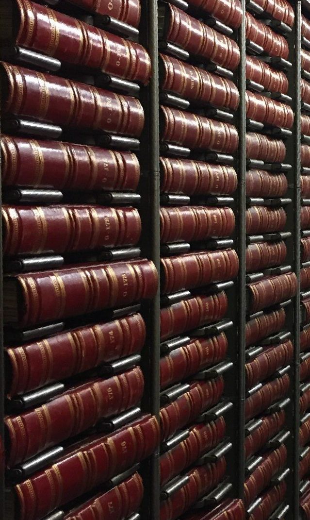A library filled with lots of red books on shelves.