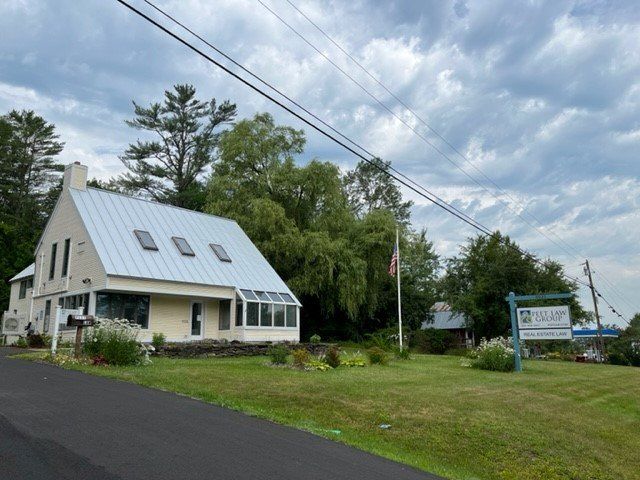 A white house with a metal roof is sitting on the side of a road