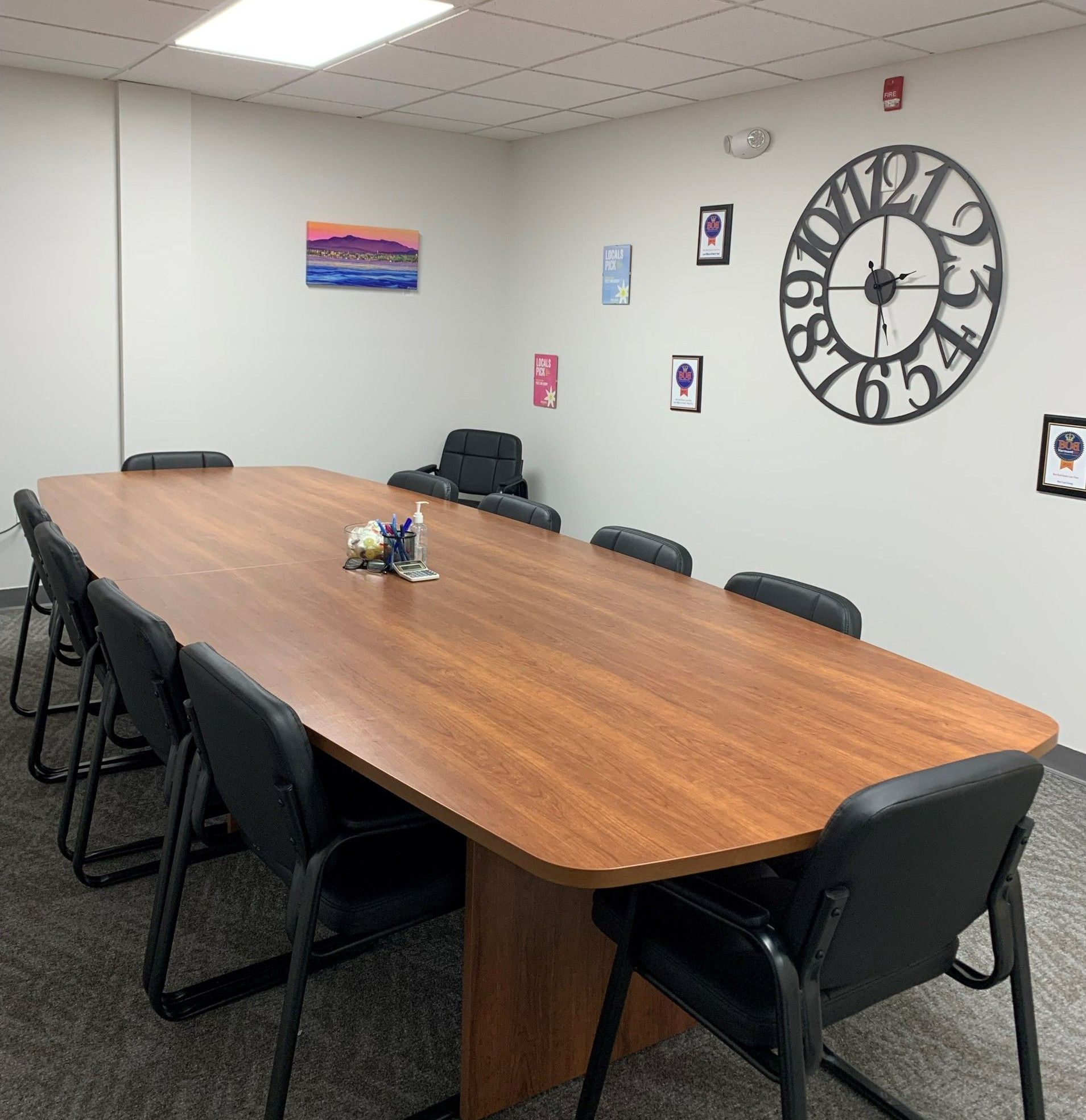 A conference room with a long table and chairs and a clock on the wall