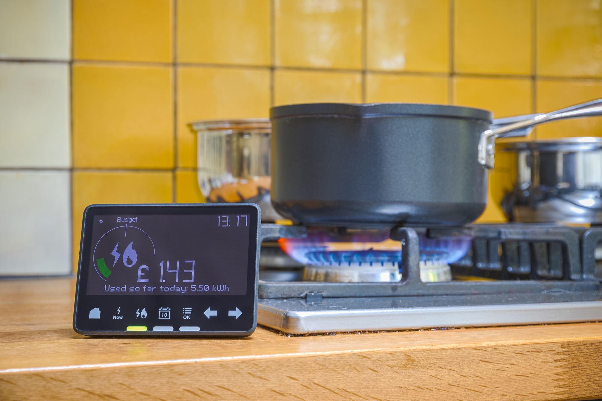 Black kitchen pot simmering on a gas stove beside a digital timer on a wooden counter