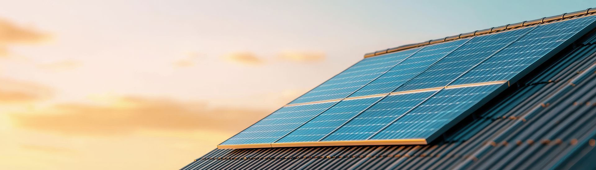 Solar panels on a rooftop at sunset with a warm orange sky