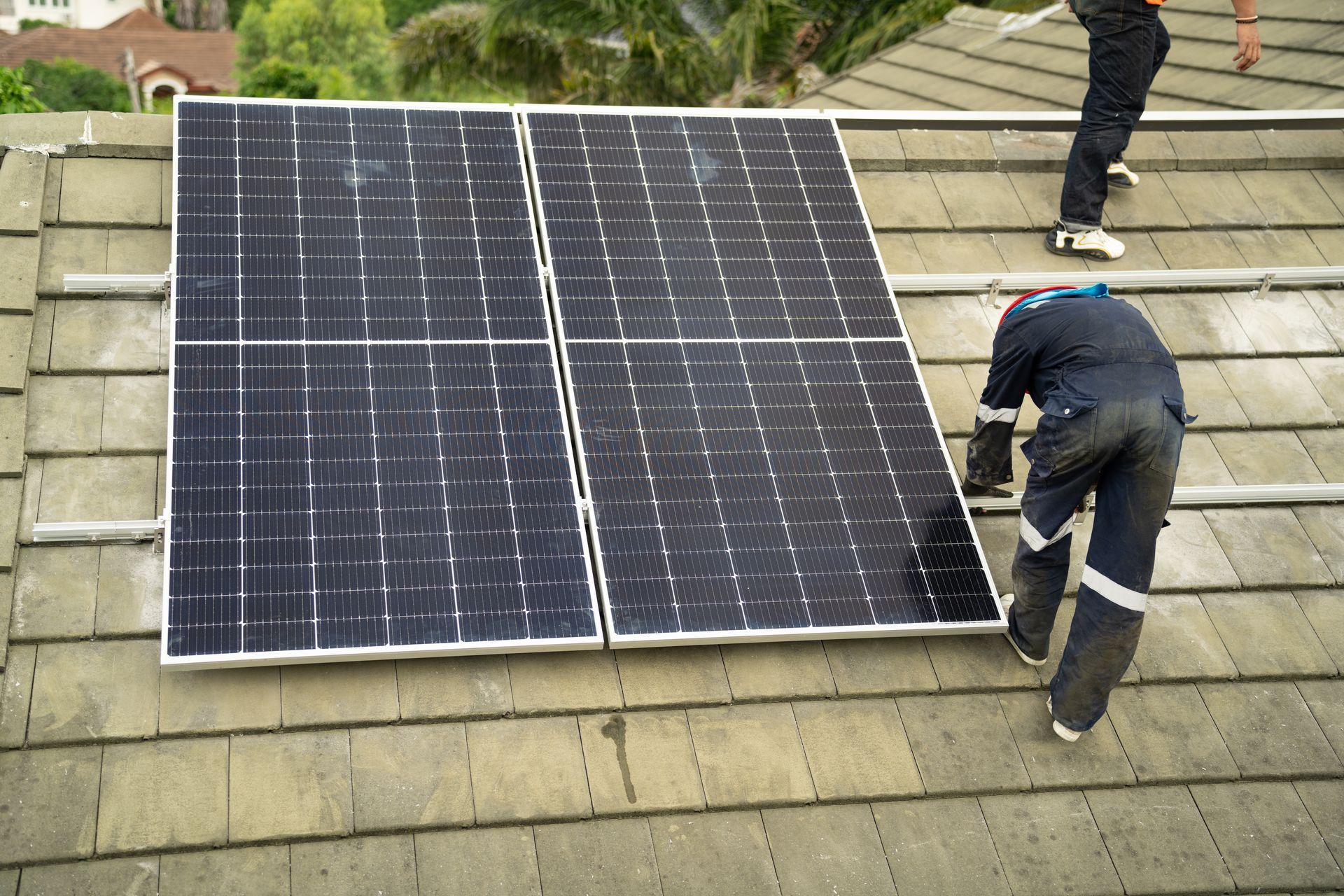 Workers installing solar panels on a shingled roof