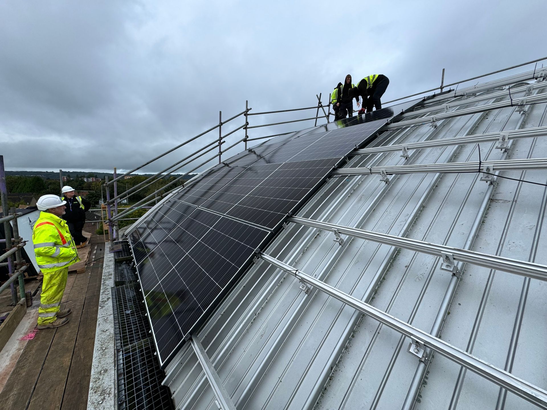 Workers installing solar panels on a rooftop under a clear sky.