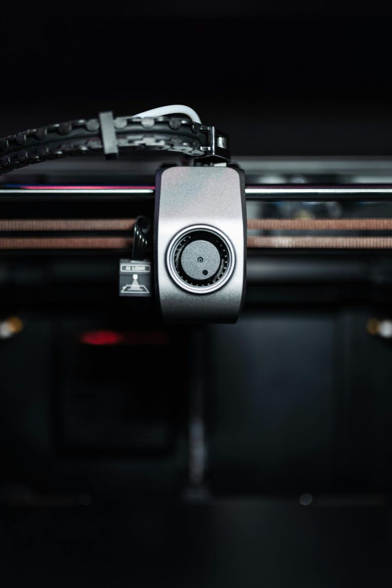 Close-up of a metal padlock hanging from a black and pink 3D printer frame