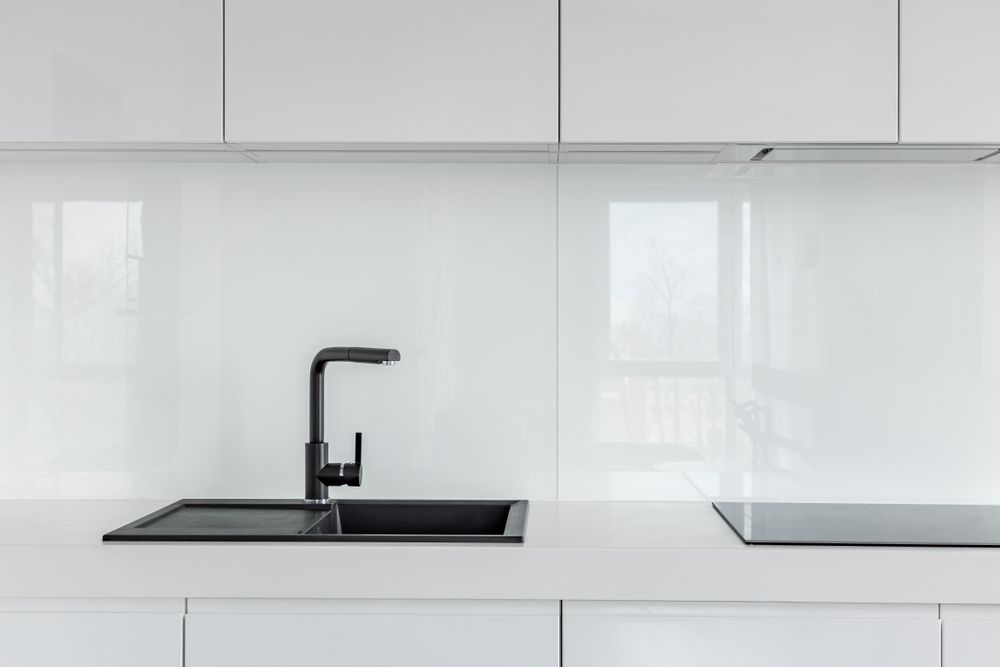 Modern white kitchen with black sink and faucet, glossy backsplash, and empty countertop — Kreuzer Cabinets In East Wagga Wagga, NSW