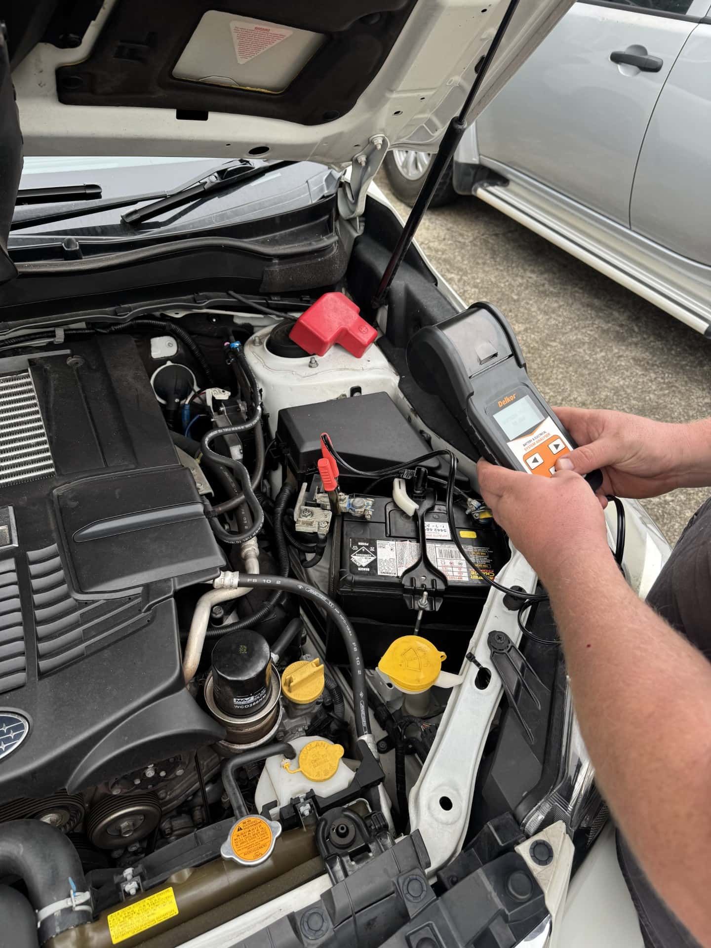 A person is working on the engine of a car. — Noosa Batteries in Noosaville, QLD