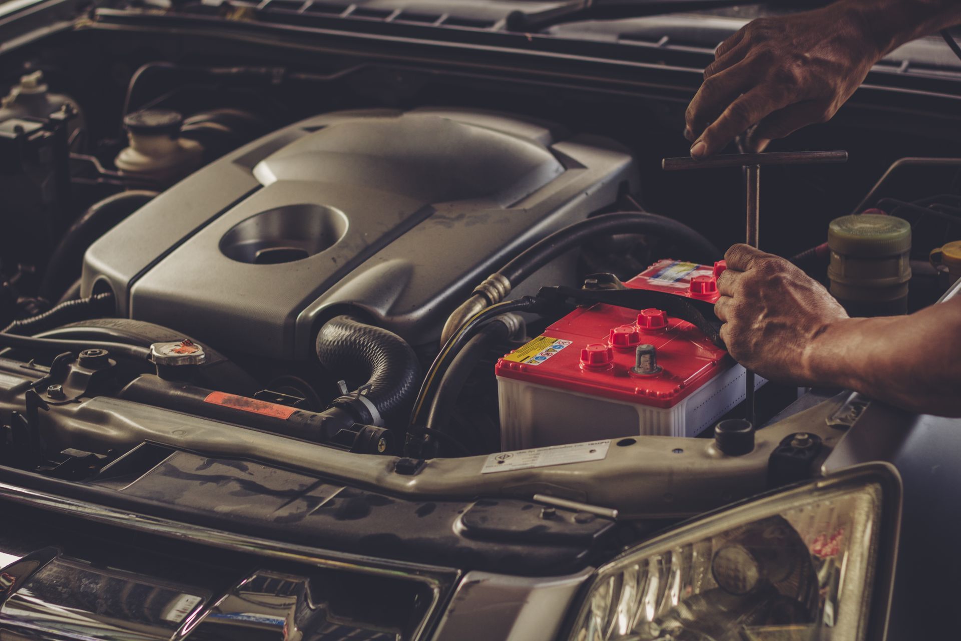 A Man is Working on the Engine of a Car With a Wrench — Noosa Batteries in Noosaville, QLD