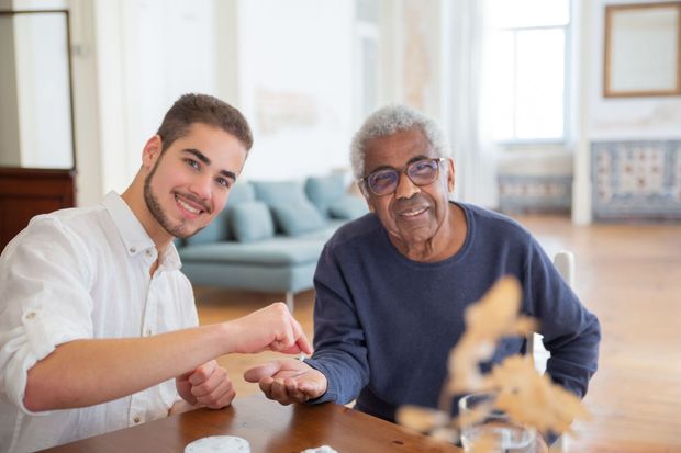 Two people smiling and playing a board game at a table in a bright living room