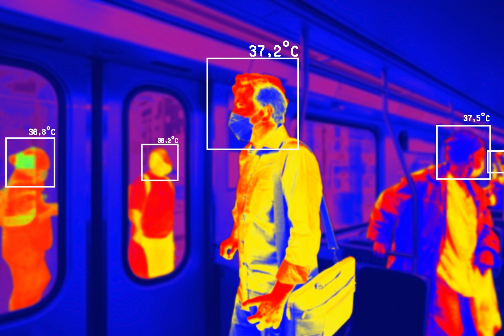 Thermal scan of commuters standing inside a train, with temperature boxes highlighting faces and bodies